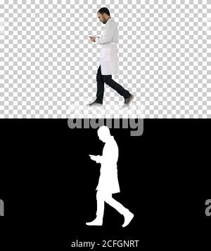 Male doctor walking and using mobile phone, Alpha Channel Stock Photo
