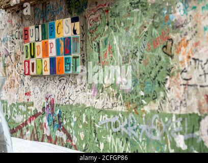 Colourful tiles spell out Budapest 3 times on a wall of a ruin bar covered with patron's scribbles. Stock Photo