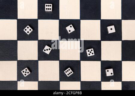 Black and white chessboard with dice showing assorted numbers placed on the black squares in an overhead background view conceptual of entertainment, Stock Photo