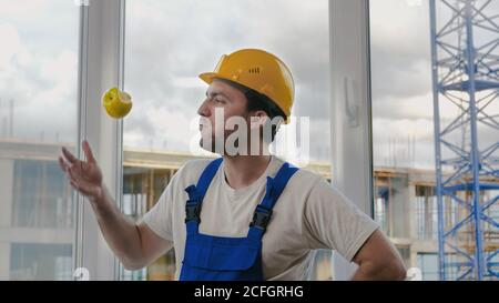Comic fail. Builder drops the apple and pics it up. Stock Photo