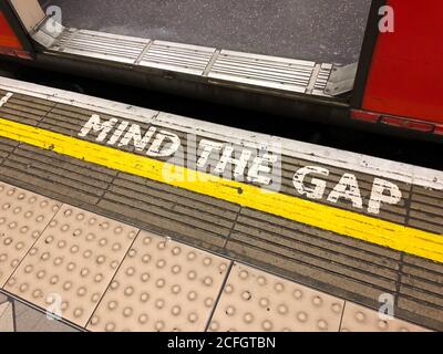 London, UK - Mar 20, 2019: Mind the gap written at the edge of the boarding area at the Train station late in the day. Stock Photo