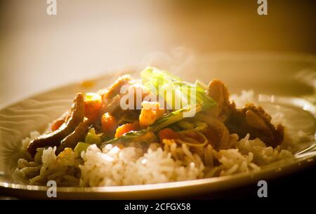 Asian stir fry and rice on plate steaming hot Stock Photo