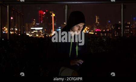 Man in hoodie hacking website at night Stock Photo