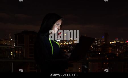Young woman browsing laptop in night city Stock Photo
