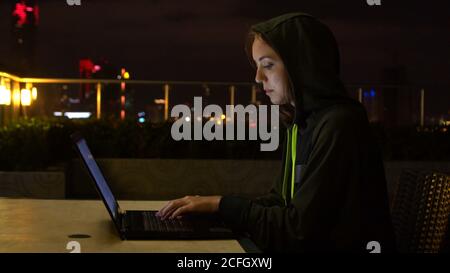 Young woman using laptop on balcony at night Stock Photo