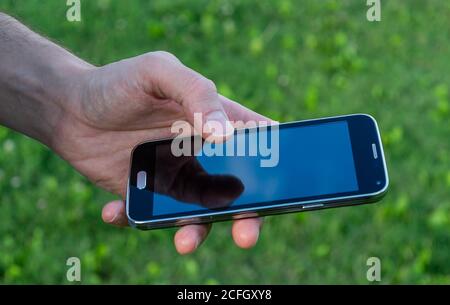 man hand holding mobile phone reflection on screen Stock Photo