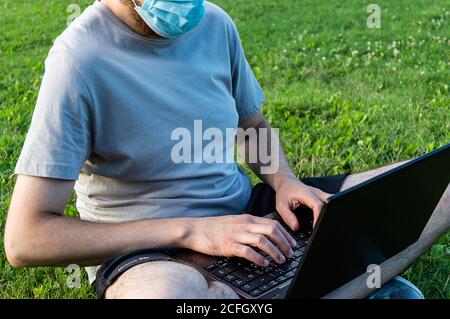 A man with laptop is sitting on the grass Stock Photo