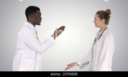 Successful team of surgeons giving high five and laughing wall on gradient background on gradient background. Stock Photo