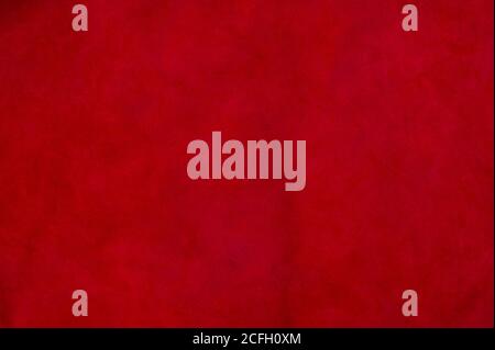 Red matte background of suede fabric, closeup. Velvet texture of seamless wine leather. Felt material macro. Stock Photo