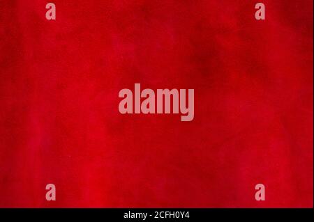 Red matte background of suede fabric, closeup. Velvet texture of seamless wine leather. Felt material macro. Stock Photo