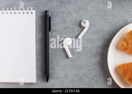 White Notepad, wireless headphones. The concept of online training, work from home, home office. Copy space. Stock Photo