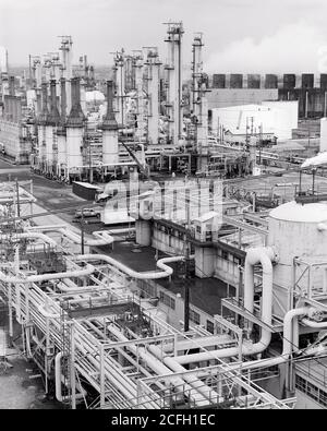 1970s OIL OR PETROLEUM REFINERY INDUSTRIAL PROCESSING PLANT FOR CRACKING REFINING TRANSFORMING CRUDE OIL INTO USEFUL PRODUCTS - i6501 HAR001 HARS KEROSENE PETROCHEMICAL CRUDE OILS REFINING OR ASPHALT CRACKING LIQUEFIED PETROLEUM PRECISION PROCESS BLACK AND WHITE DISTILLATION FOSSIL FUEL HAR001 OLD FASHIONED TOWERS Stock Photo