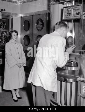 1950s YOUNG TEENAGE BOY IN SPORTS JACKET BUYING TWO MOVIE TICKETS AT BOX OFFICE WHILE SMILING GIRL HIS DATE WAITS IN CLOTH COAT - j8351 HAR001 HARS CINEMA NOSTALGIC FILM PAIR ROMANCE SUBURBAN URBAN THEATER RELATIONSHIP OLD TIME BUYING NOSTALGIA OLD FASHION 1 JUVENILE STYLE YOUNG ADULT TICKETS LIFESTYLE FEMALES MARRIED SPOUSE HUSBANDS COPY SPACE FRIENDSHIP FULL-LENGTH HALF-LENGTH LADIES PERSONS MALES TEENAGE GIRL TEENAGE BOY ENTERTAINMENT B&W MOVIES PARTNER DATING HAPPINESS FILMS CINEMAS HIS LEISURE EXCITEMENT ATTRACTION CONNECTION COURTSHIP STYLISH TEENAGED BOX OFFICE MOTION PICTURE Stock Photo