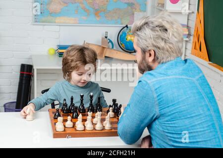 Pupil kid thinking about his next move in a game of chess. Concentrated  little boy sitting at the table and playing chess Stock Photo - Alamy