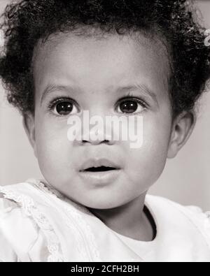 1960s CLOSE-UP PORTRAIT OF AFRICAN-AMERICAN BABY GIRL WITH BIG EYES LOOKING OFF CAMERA  - n1971 HAR001 HARS HEALTHINESS HOME LIFE COPY SPACE INSPIRATION EXPRESSIONS B&W BUG-EYED PRETTY HEAD AND SHOULDERS AFRICAN-AMERICANS AFRICAN-AMERICAN BLACK ETHNICITY CONCEPTUAL CLOSE-UP PLEASANT WIDE-EYED AGREEABLE CHARMING GROWTH JUVENILES LOVABLE PLEASING ADORABLE APPEALING BABY GIRL BLACK AND WHITE HAR001 OLD FASHIONED AFRICAN AMERICANS Stock Photo