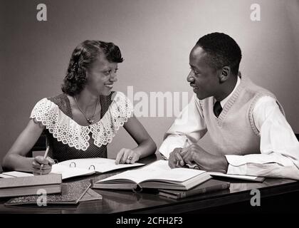 1950s AFRICAN-AMERICAN COUPLE COLLEGE STUDENTS STUDYING TOGETHER TALKING SMILING NOTEBOOKS BOOKS OPEN ON TABLE - n638 HAR001 HARS 1 STYLE COMMUNICATION YOUNG ADULT TEAMWORK INFORMATION LIFESTYLE SATISFACTION FEMALES STUDIO SHOT HEALTHINESS COPY SPACE FRIENDSHIP FULL-LENGTH LADIES PERSONS INSPIRATION MALES CONFIDENCE B&W GOALS DREAMS HAPPINESS DISCOVERY UNIVERSITIES AFRICAN-AMERICANS AFRICAN-AMERICAN KNOWLEDGE NOTEBOOKS BLACK ETHNICITY PRIDE OPPORTUNITY HIGHER EDUCATION CONNECTION STYLISH SUPPORT COLLEGES TOGETHERNESS YOUNG ADULT MAN YOUNG ADULT WOMAN BLACK AND WHITE HAR001 OLD FASHIONED Stock Photo