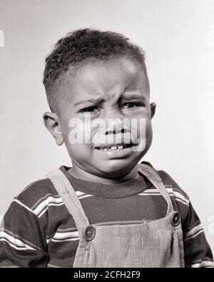 1940s 1950s PORTRAIT UNHAPPY AFRICAN-AMERICAN BOY TODDLER CRYING LOOKING AT CAMERA WEARING STRIPED TEE SHIRT CORDUROY OVERALLS - n601 HAR001 HARS FEAR COMMUNICATION WORRY LIFESTYLE STRIPED MOODY TEARS HOME LIFE TEE COPY SPACE OVERALLS CRY MALES AFRAID EXPRESSIONS TROUBLED B&W CONCERNED SADNESS WEEPING HEAD AND SHOULDERS AFRICAN-AMERICANS AFRICAN-AMERICAN CORDUROY BLACK ETHNICITY BAWLING MOOD SOBBING GLUM BABY BOY GROWTH JUVENILES MISERABLE BLACK AND WHITE HAR001 OLD FASHIONED AFRICAN AMERICANS Stock Photo