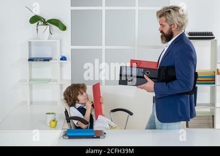 Boss and employee. Little boss and mature employee in the office. Colleagues brainstorming in talk. Old and yong business concept. Kids director Stock Photo