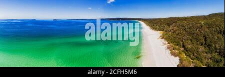 Pristine white sandy beach in Jervis bay of Australia – wide panorama from forest to bay entrance. Stock Photo