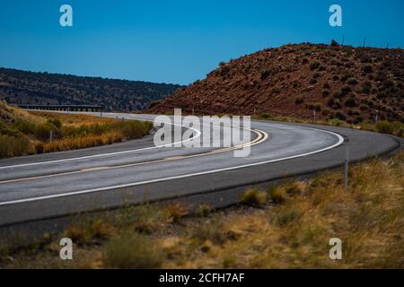 Long Desert Highway California. Landscape with rocks, sunny sky with clouds and beautiful asphalt road in the evening in summer. Stock Photo
