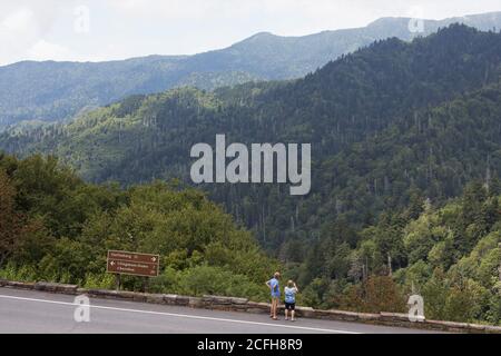 A couple next to the road taking a picture of the mountains at Great Smoky Mountains National Park in the United States. Stock Photo