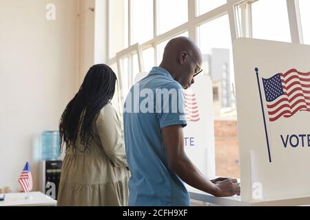 Back view portrait of young African-American people standing in voting booth and thinking, copy space Stock Photo