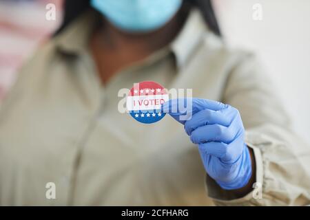 Close up of unrecognizable African-American woman holding I VOTED sticker while standing at polling station on post-pandemic election day, copy space Stock Photo