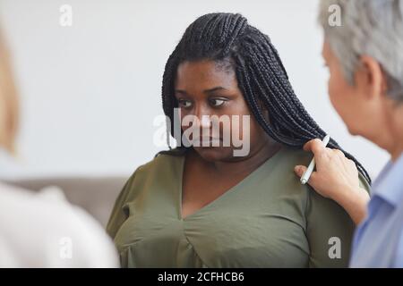 Portrait of young African-American woman sharing story during support group meeting with mature female psychologist comforting her, copy space Stock Photo