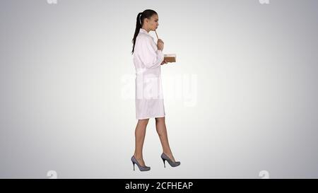 Successful medical doctors making notes while walking on gradient background. Stock Photo
