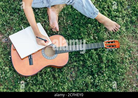 songwriter create and writing notes,lyrics in the book on grass at parks. Stock Photo