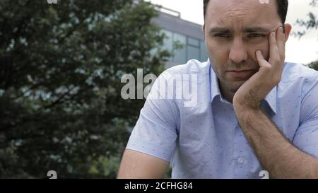 Man is severely depressed and sad sitting in a park. Stock Photo