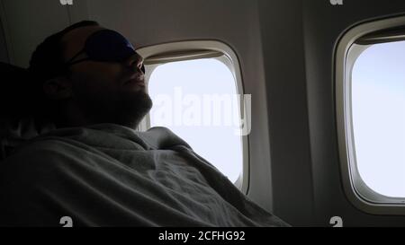 Rest and comfortable flight in the plane. Man in a mask for slee Stock Photo