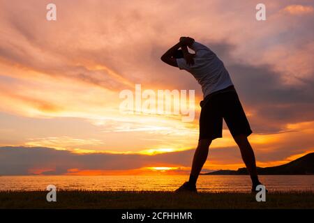 Young sports man doing stretching after run at the beach Stock Photo