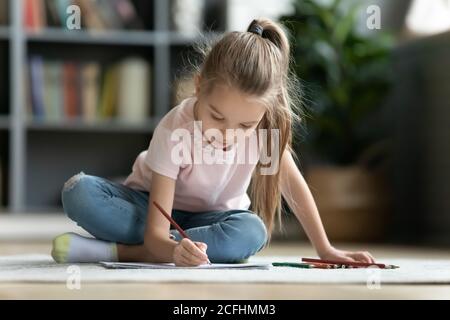 Pretty little girl playing on warm floor, drawing with pencils Stock Photo