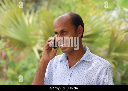 Casual dressed smiling Asian man talking on mobile phone Stock Photo