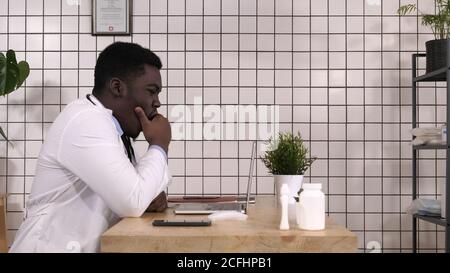 Afro american doctor working and being tired, having neck pain. Stock Photo