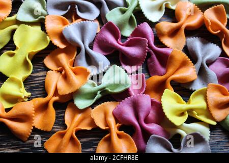 Festive multicolored farfalle pasta bows on a dark wooden background Stock Photo