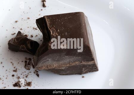 a large chopped piece of chocolate lies on a white ceramic plate Stock Photo