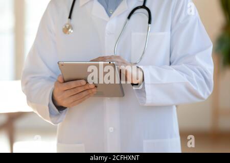 Close up doctor therapist wearing uniform holding computer tablet Stock Photo