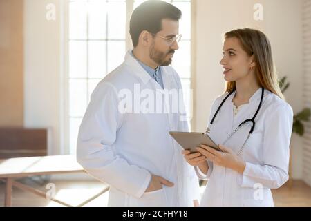 Smiling young nurse and doctor talking in office, working together Stock Photo