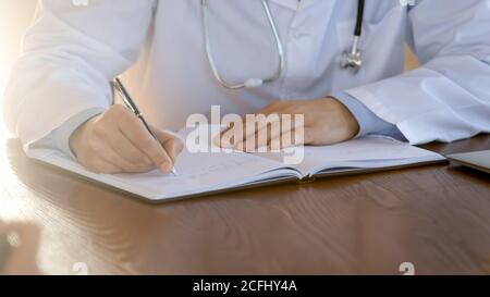 Close up doctor writing in patient card, working with documents Stock Photo