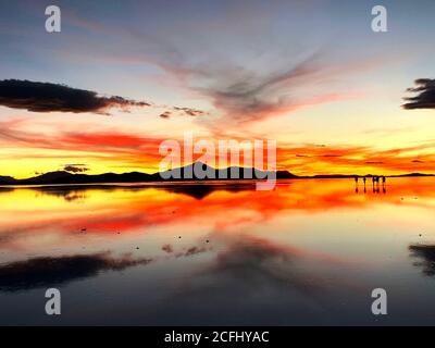 Spectacular sunset over Salt Flats of Salar de Uyuni, Bolivia. Magical sky reflection in the water. Impressive wilderness nature of South America. Stock Photo