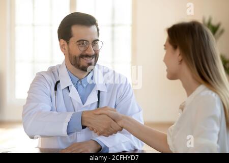 Close up smiling doctor shaking patient hand at meeting Stock Photo