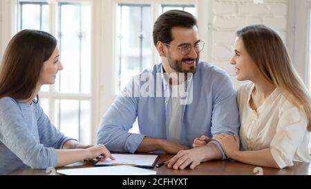 Smiling married couple holding hands at meeting with realtor Stock Photo
