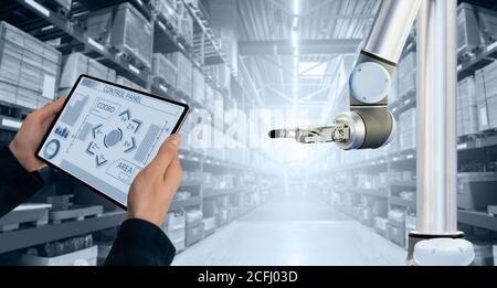 Warehouse manager with digital tablet controls robot arm Stock Photo