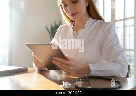 Close up focused woman doctor working on computer tablet Stock Photo