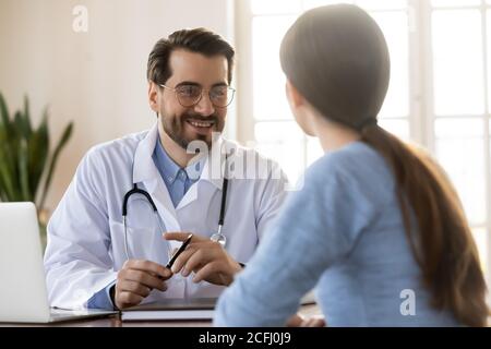 Smiling young doctor therapist listening to patient complaints at meeting Stock Photo