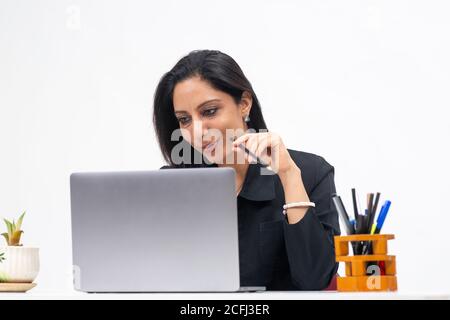 Portrait of professional Indian businesswoman working from her computer, Freelancer, work from home, Corporate lady holding pencil and concentrating. Stock Photo