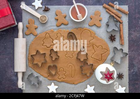 Top view on rolled out dough for christmas gingerbread cookies with accessories on a parchment paper. Stock Photo