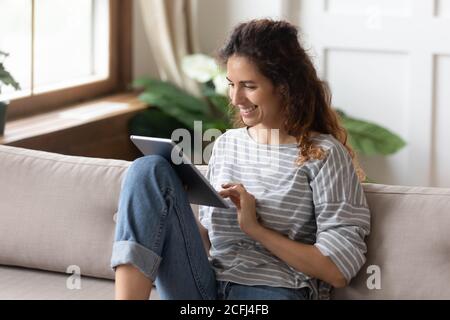 Woman sitting on sofa using tablet device buying on internet Stock Photo